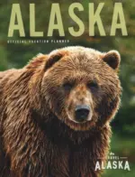 Alaska Vacation Guide: A panoramic view of a snow-capped mountain range in Alaska with a turquoise glacial lake in the foreground.