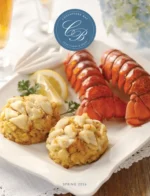 Chesapeake Bay Crab Cakes: Freshly broiled Maryland style crab cakes served with a lemon wedge and fresh herbs.