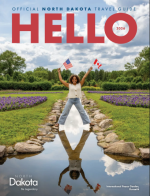 North Dakota Vacation Guide: Scenic view of the North Dakota Badlands with layered rock formations and wild bison grazing in the foreground.