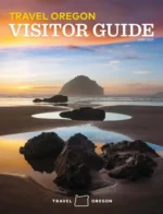 Oregon Vacation Guide: A scenic view of Haystack Rock on the Oregon coast with waves crashing against the shore under a misty sky.